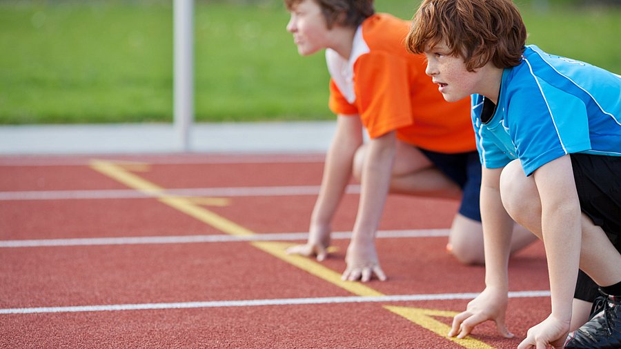 Zwei Jugendliche in Startposition für einen Wettlauf