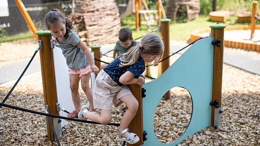 Drei Kinder klettern auf einem Spielgerät aus Seilen