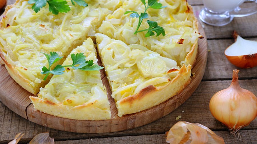 1 Kuchen Quiche mit rohen Zwiebeln dekoriert.